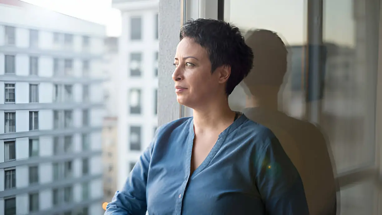 Thoughtful Woman Looking Out Window – Executive Coaching Challenge - Reputation Matters Thoughtful woman gazing out window with a serious, reflective expression