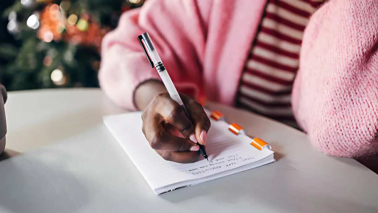 Close-up of hands writing in a notebook during reflection